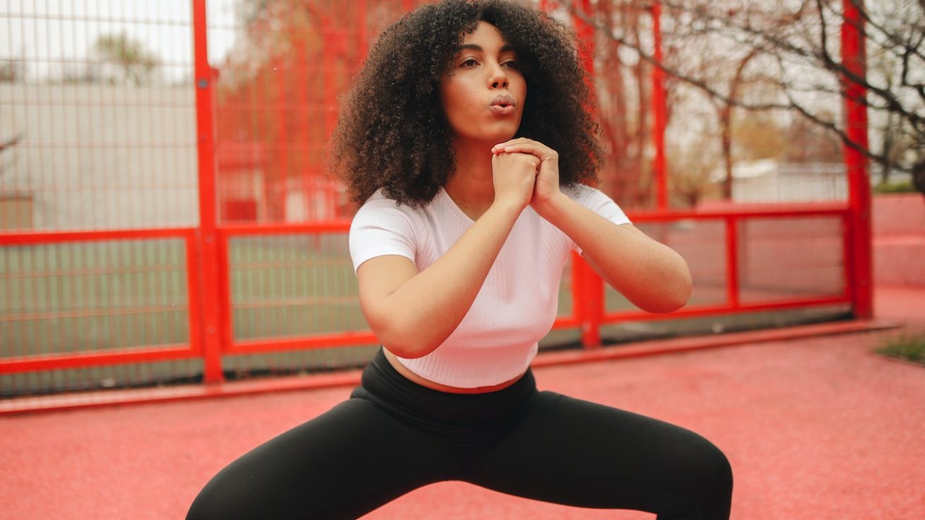 A woman with curly hair exercising outdoors