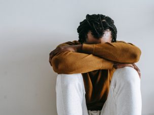 a depressed black man sitting with his head down